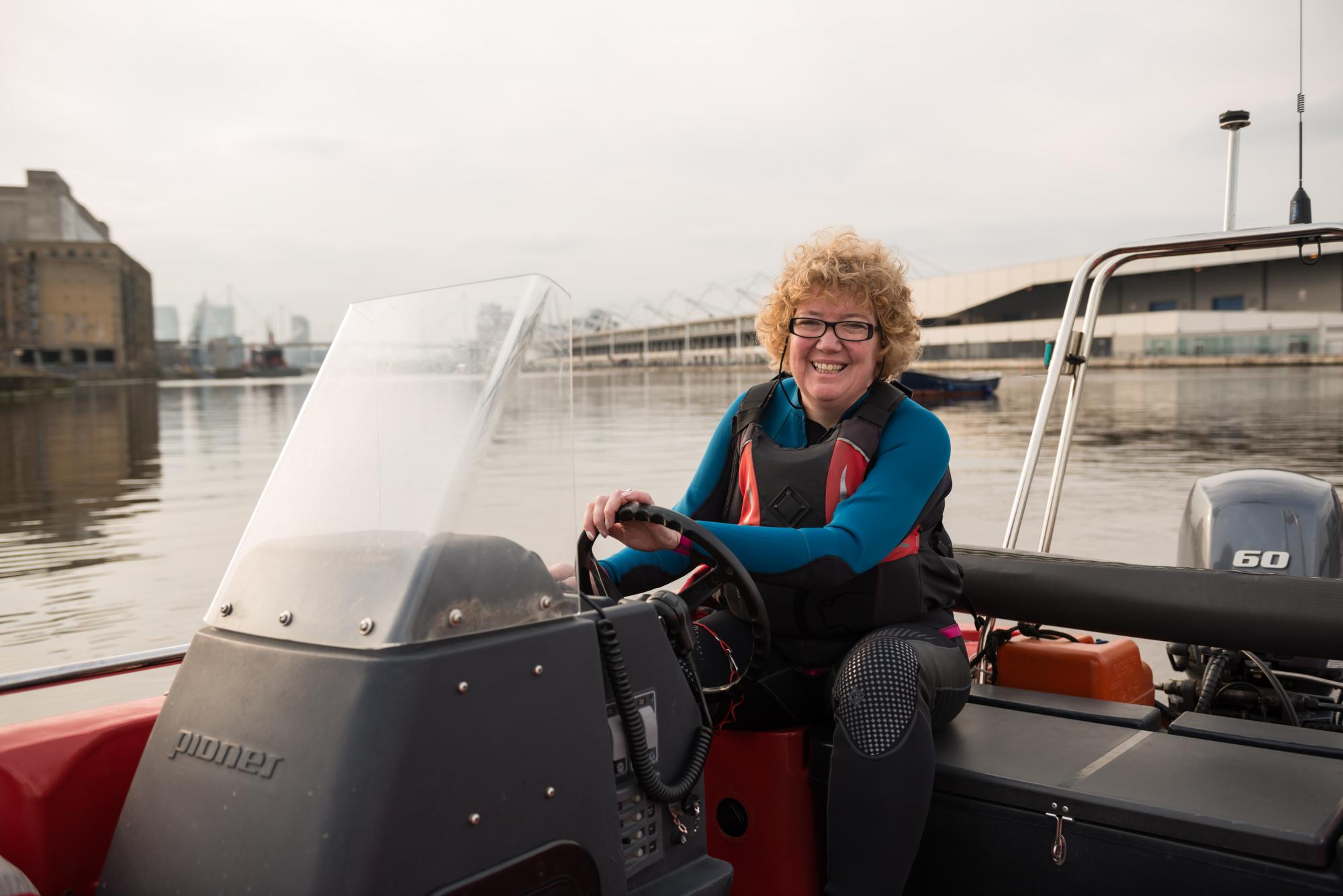 Smiling lady volunteering as a watersports instructor and driving a boat 