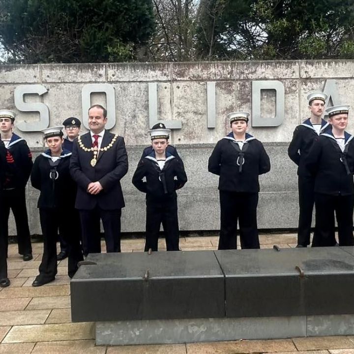 Cadets stand at ease in front of memorial