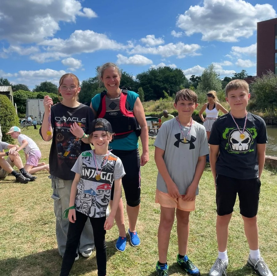 Boating instructor plus some young cadets smile at the camera, dressed for boating activities.