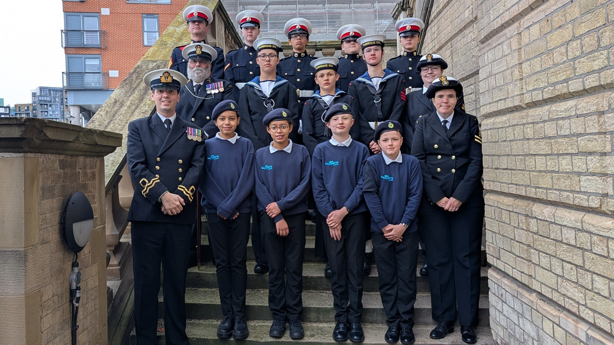 The Cadets and Adult Volunteers from Sea Cadets Cambridge after the South East District Trafalgar Parade stood on the stairs outside of the Old Custom House in Ipswich.