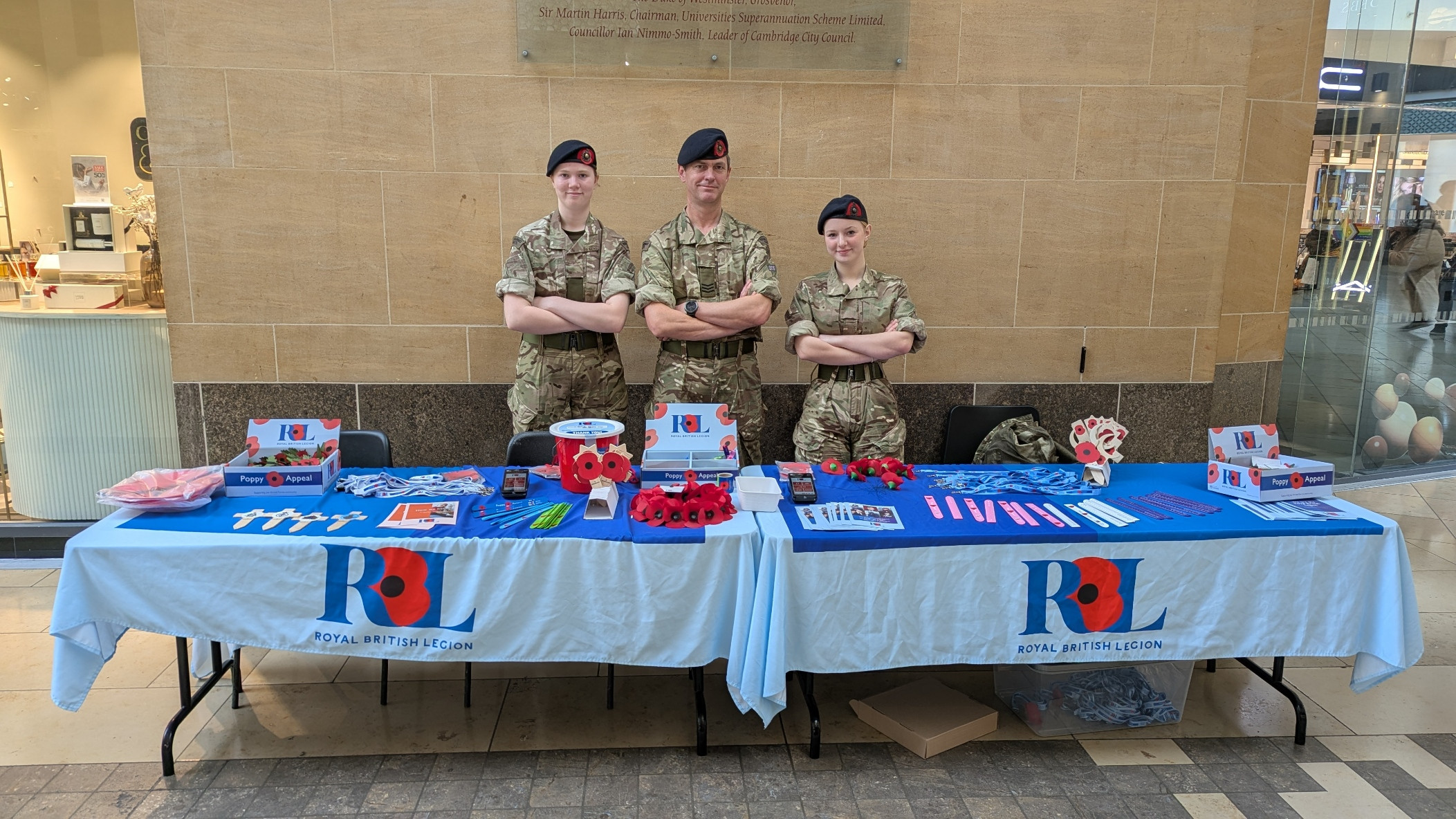 Three Royal Marines Cadets stood behind a Royal British Legion table while collecting for the Poppy Appeal.