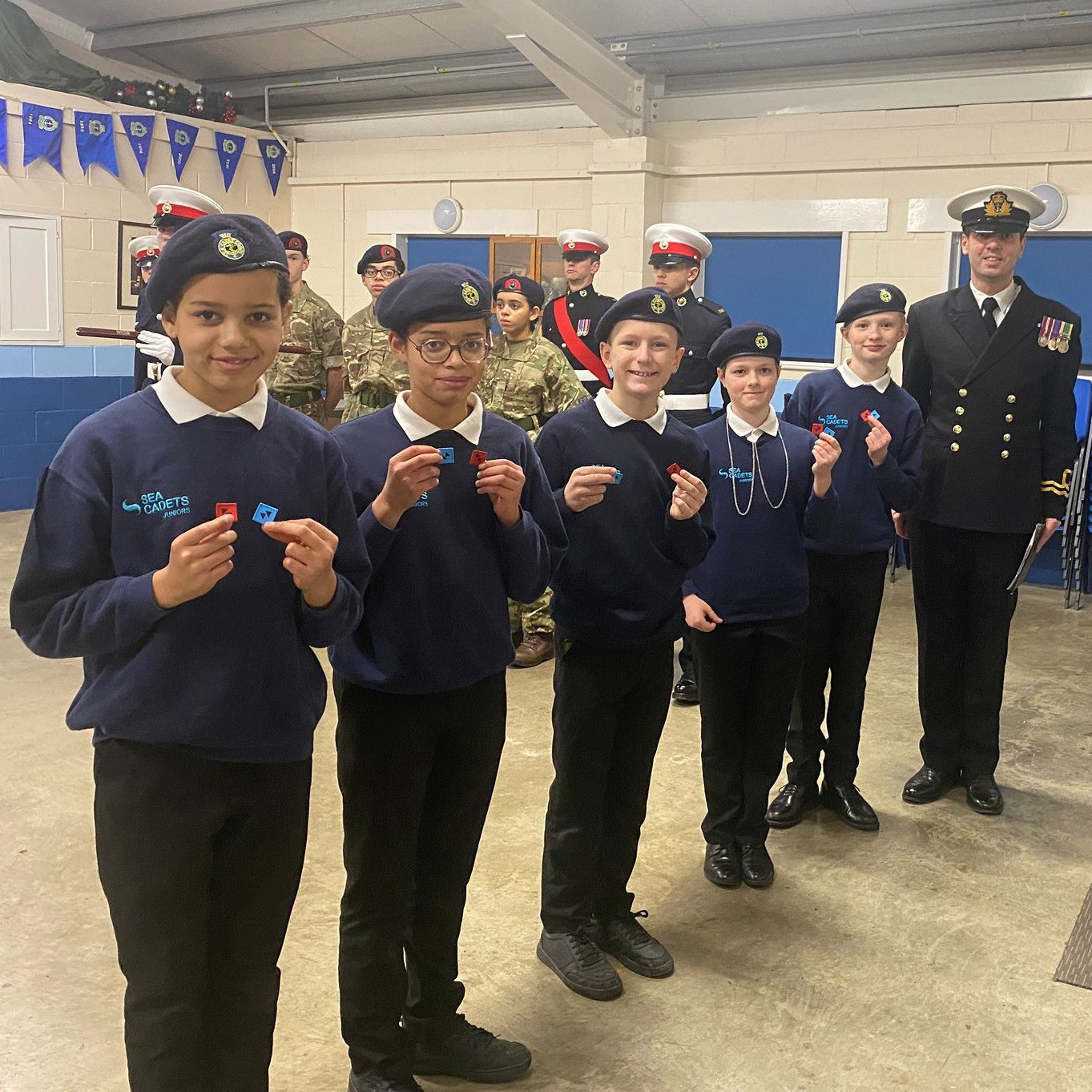 Junior Cadets from the Unit receiving their Red and Blue badges from the Commanding Officer, Lieutenant Jones.
