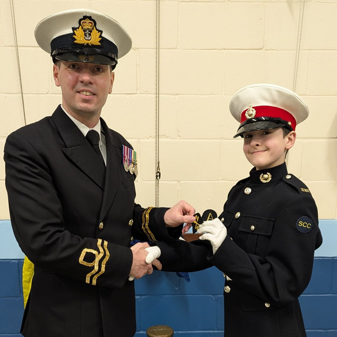 Marine Cadet Recruit Wagstaff receiving his Rowing Touring Module and RYA Youth Windsurfing Stage 1 badges from the Commanding Officer, Lieutenant Jones.
