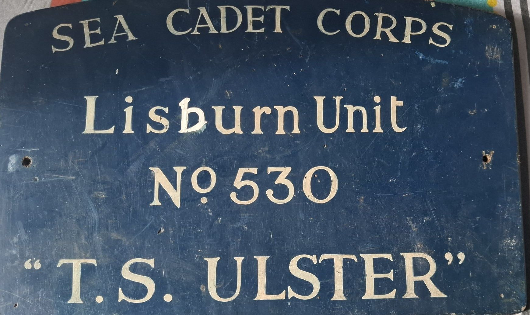 A blue sign reading "Sea Cadet Corps Lisburn Unit No. 530 T.S. Ulster"