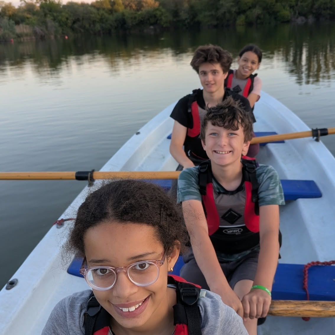 Four smiling Cadets in a Trinity 500 rowing boat.