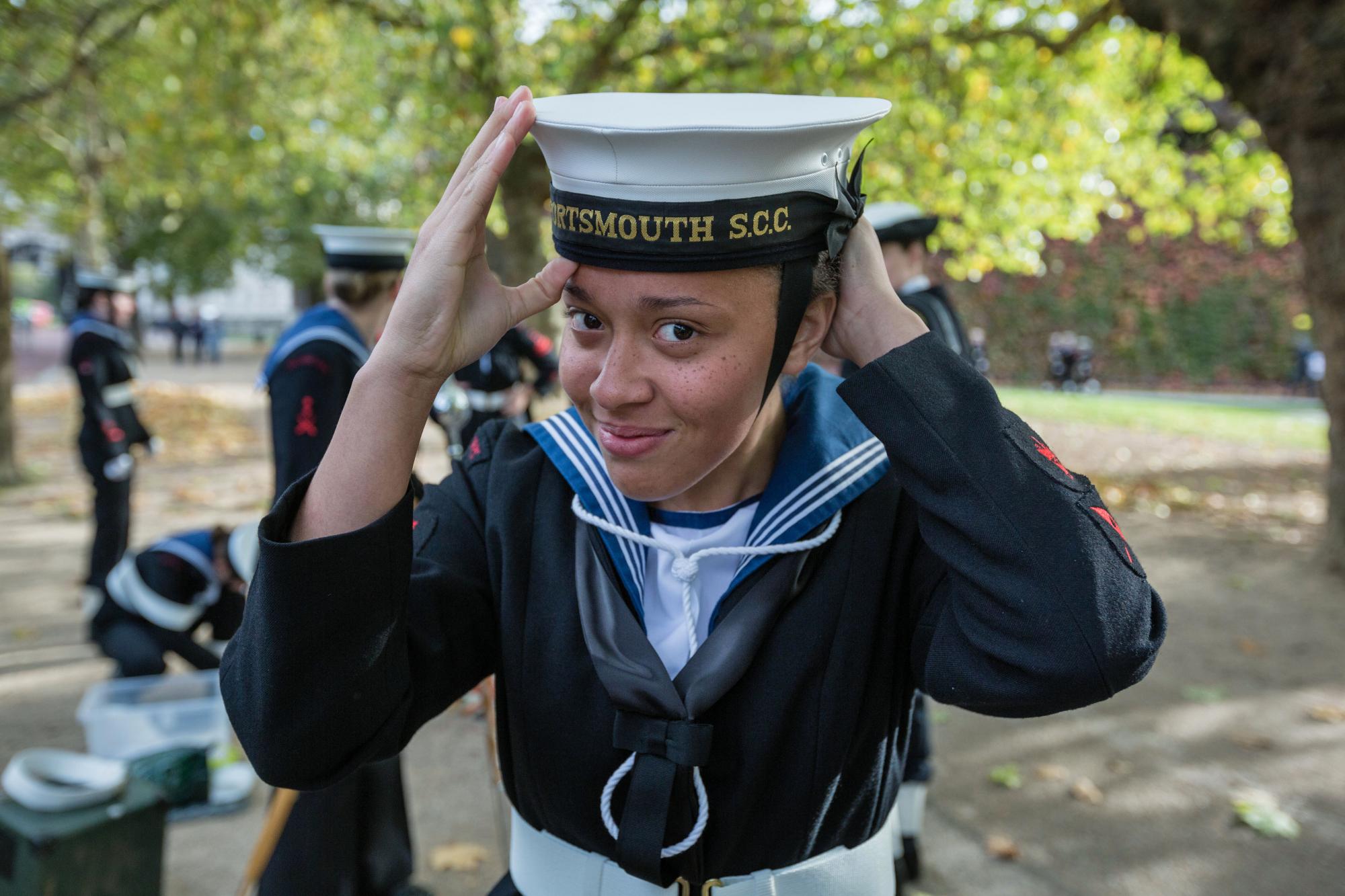 Girl Sea Cadet smiling and adjusting her uniform hat